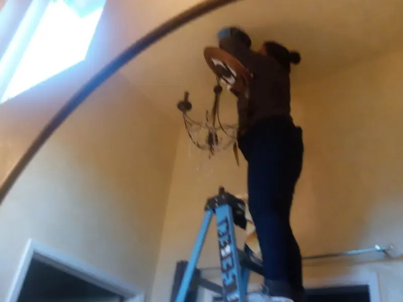 Electrician installing a chandelier in a Burleson residence